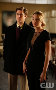A beautiful blonde woman stands beside a handsome man. Both wear black. They are inside an NYC apartment.