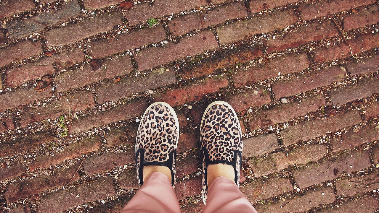 Cheetah print slip on sneakers along a brick pathway