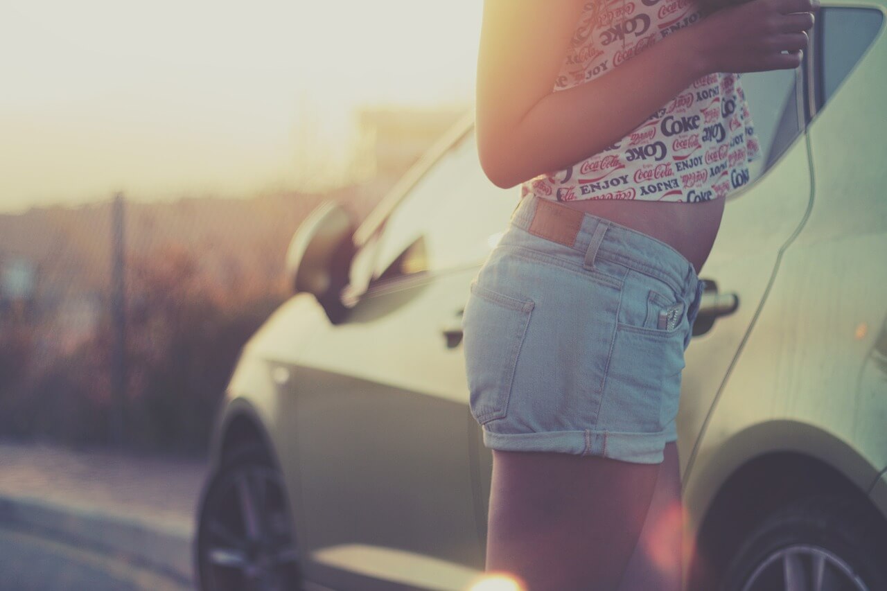 Girl in jean shorts against a car